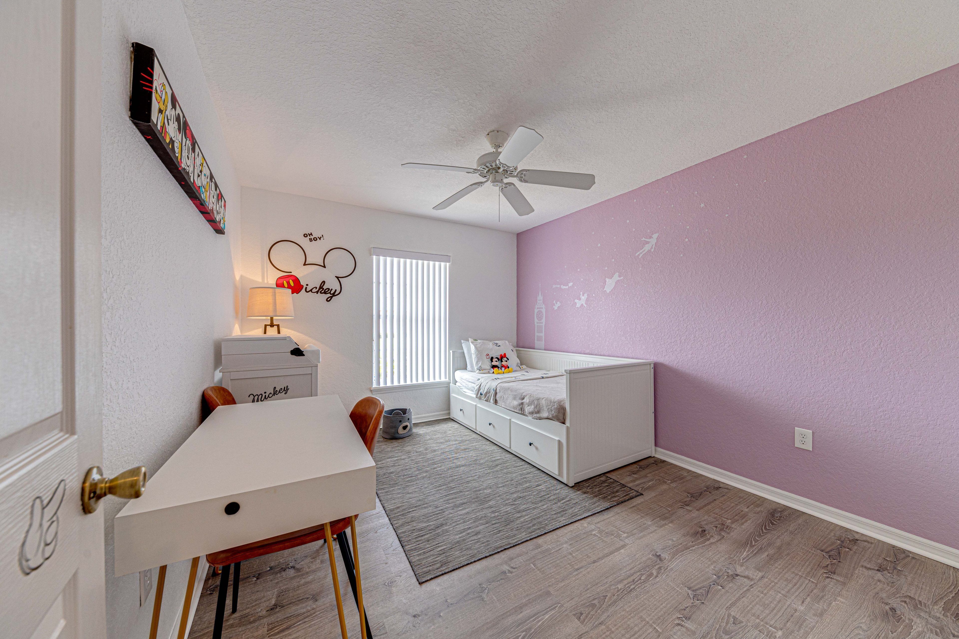 A child's bedroom with a bed, desk, chair, and a ceiling fan.