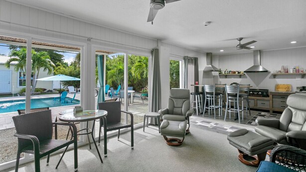 Un salón espacioso con piscina, mobiliario de exterior y cocina.