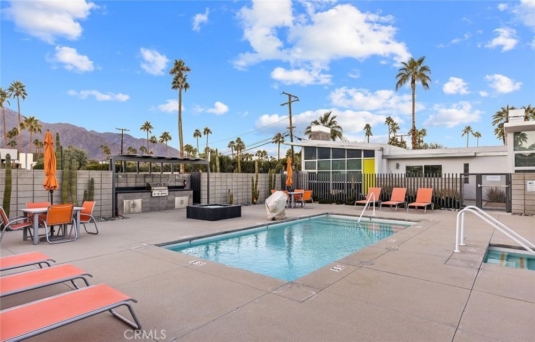 Un espace piscine avec des chaises longues, un jacuzzi et des palmiers.