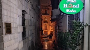 Een smalle steeg die leidt naar een gebouw met een bordje voor 'Pera Hotel Baku'.