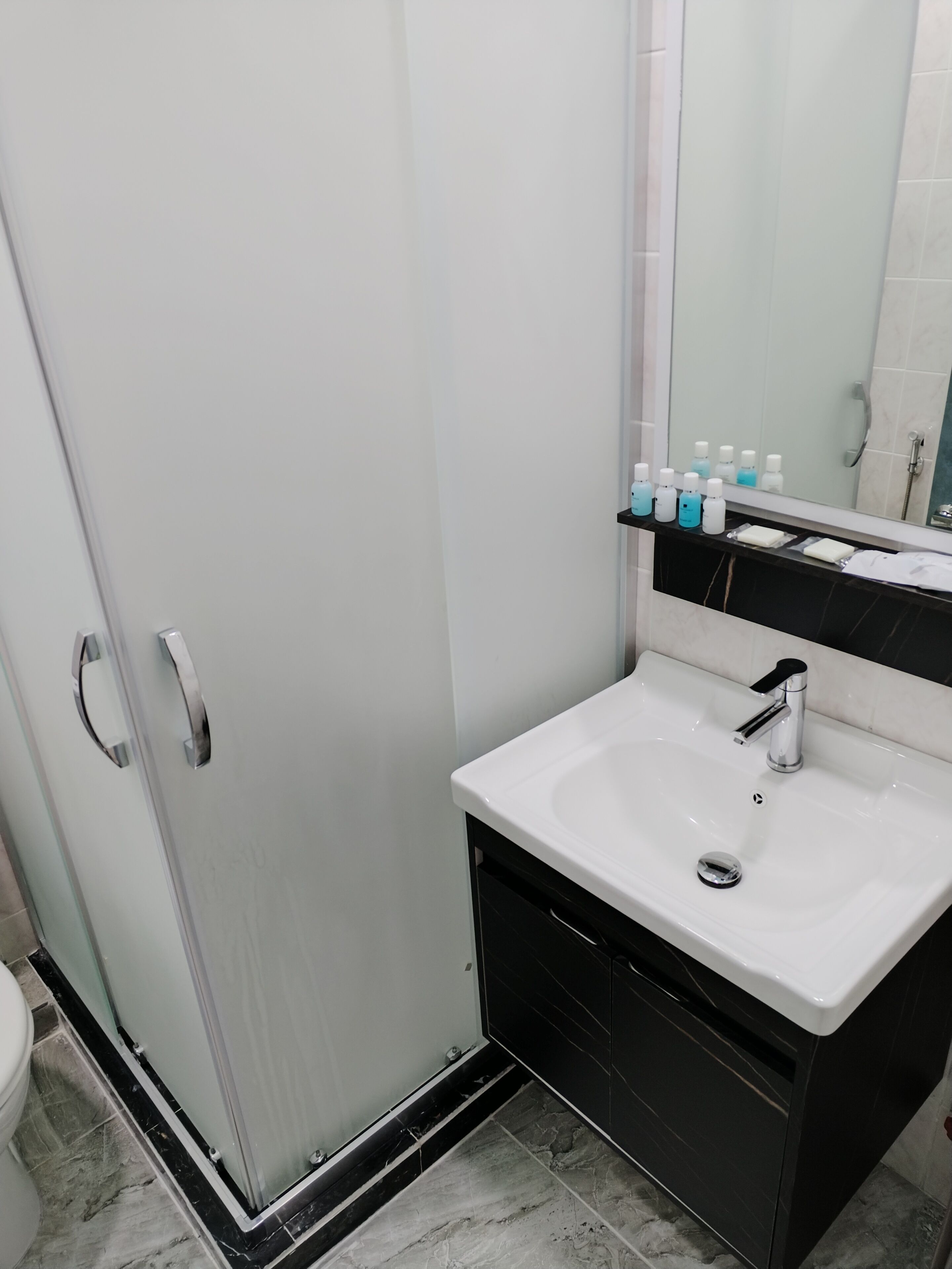A bathroom with a white sink, a mirror, and a glass shower enclosure.