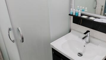A bathroom with a white sink, a mirror, and a glass shower enclosure.