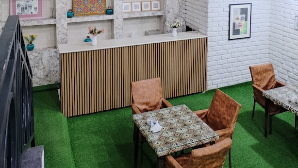 Een hotel lobby met een marmeren receptiebalie, een trap met een zwarte balustrade en een tapijt in groen.
