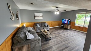 A living room with two grey sofas, a coffee table, a TV, and a wooden accent wall.