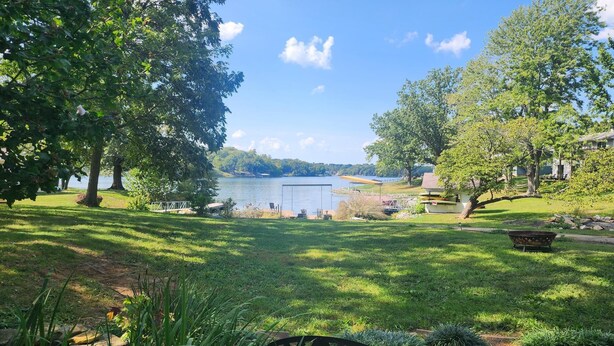 A lakeside view with a grassy area, a dock, and a boat.