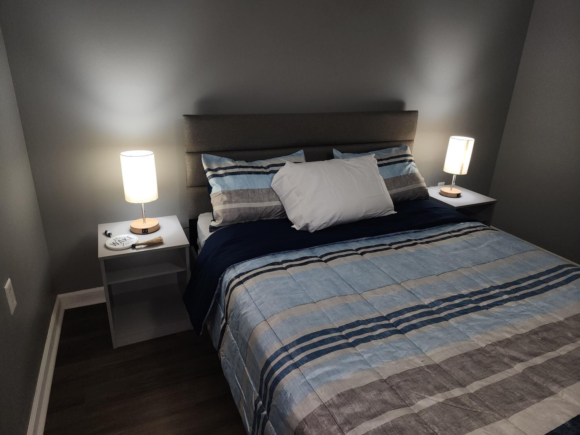 A bedroom with a bed, two bedside tables, and two lamps.