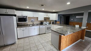 A modern kitchen with white cabinets, a granite countertop, a built-in stove, and a refrigerator.