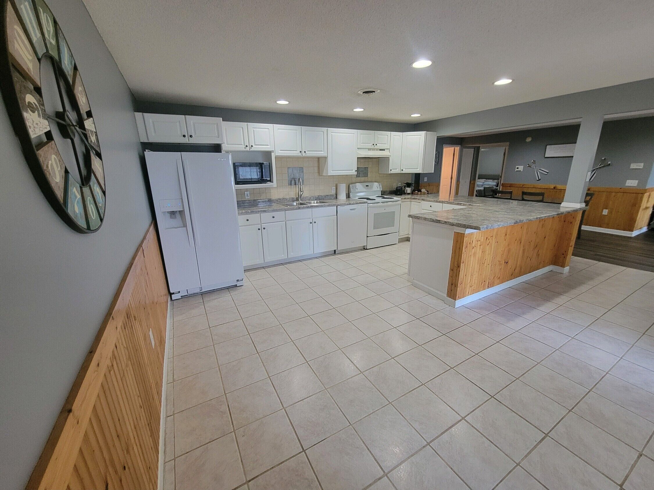 A modern kitchen with white cabinets, a central island, and a microwave above the counter.