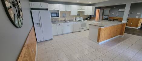 A modern kitchen with white cabinets, a central island, and a microwave above the counter.
