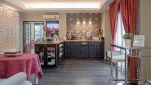 A modern kitchen with dark cabinets, a breakfast bar, and a dining area with a table set for two. - The star of sathon Luxury king room 502 (Krung Thep Maha Nakhon)