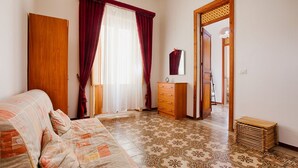 A bedroom with a bed, a dresser, a mirror, and a patterned floor. - GuestHost - Castellammare Stella Apartment with Terrace (Castellammare del Golfo)