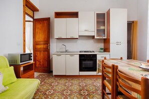A compact kitchen with white cabinets, a microwave, an oven, and a dining table with chairs.