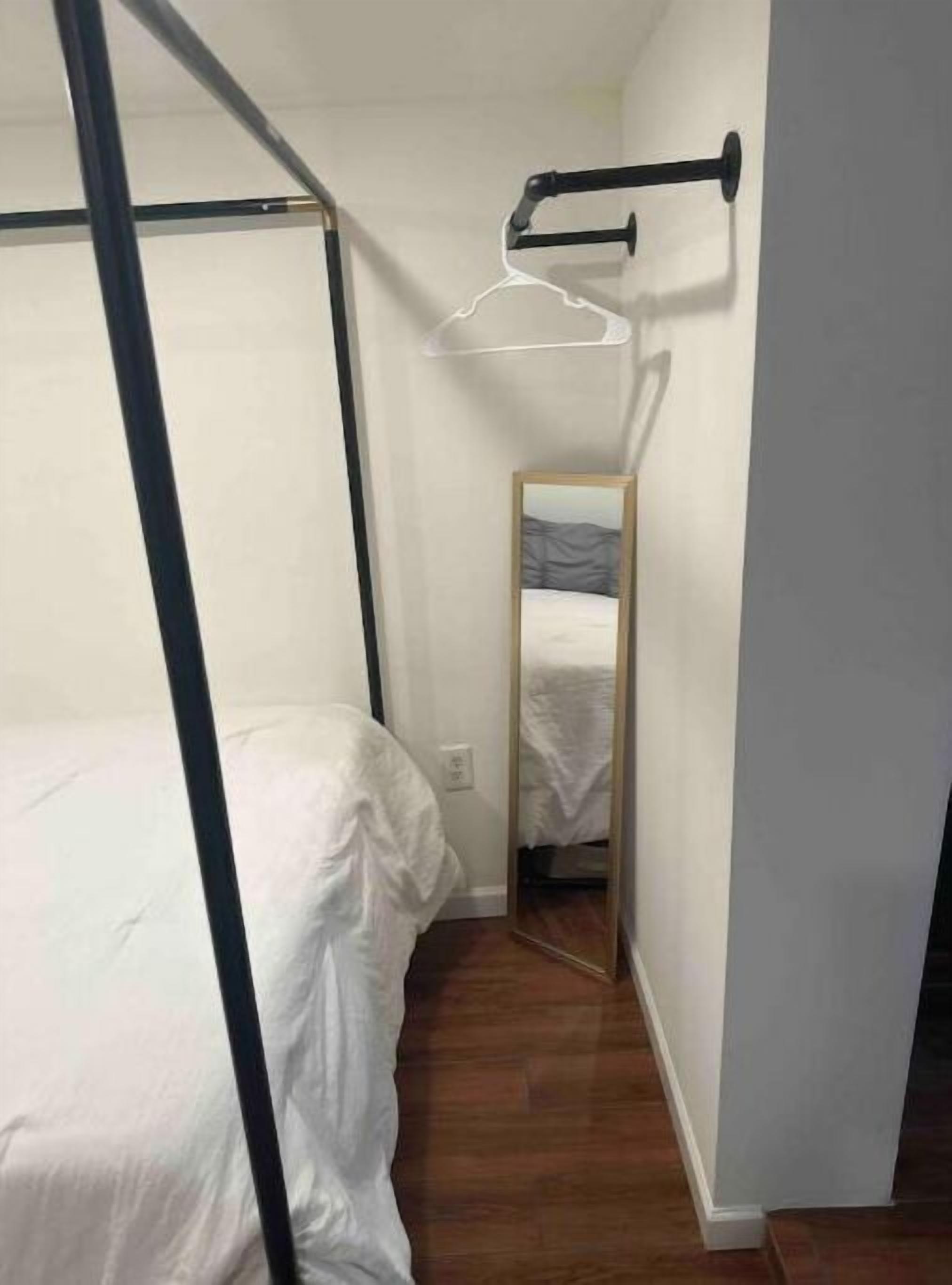 Une chambre à coucher avec un lit, un miroir et un cadre de lit en métal noir.