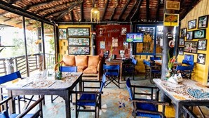 A restaurant with wooden tables and chairs, a red wall with posters, and a tiled floor. - Finca-hotel Montecarlo by Hope (Antioquia)