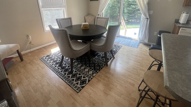 A dining area with a round table, four chairs, a black and white patterned rug, and a view of the outdoors through a glass door. - Peaceful Hideaway! New Listing (Roscommon)