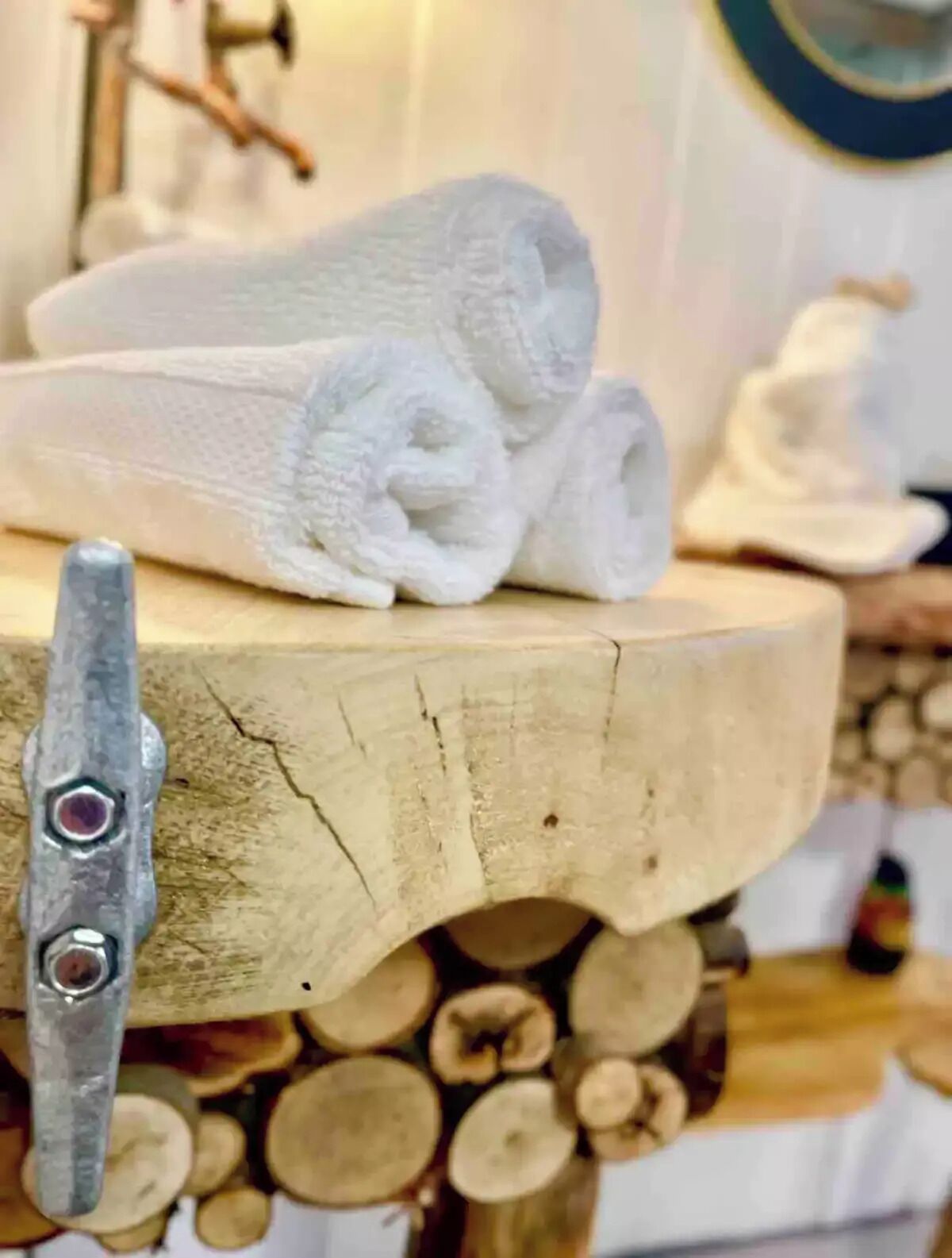 Een handdoek op een houten standaard met een metalen knijper, een rustieke houten muur en een stapelhout op de achtergrond.