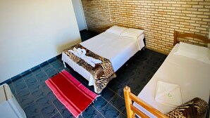 Una cama individual con una colcha estampada de cebra y una manta roja, una silla de madera y una pared con diseño de ladrillo.