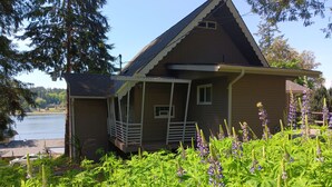 Une maison avec un porche, une petite terrasse et une vue sur un lac.