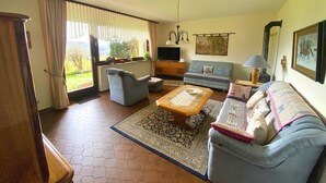 A living room with a sofa, armchair, coffee table, and a television.