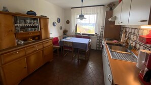 A kitchen with wooden cabinets, a dining table, and a window with curtains.