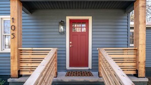 A wooden front porch with a red door, a small lantern, and a number '105' on the wall. - Collegeside Cottage / Downtown Franklin Park/Brevard College 3Bd Pets ok (Brevard)