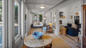 A spacious living area with a large window, a wooden table with a bowl, a sofa, and a lamp. - Renovated Center Island Home & Garage Apt 4bd/3ba (Fripp Island)