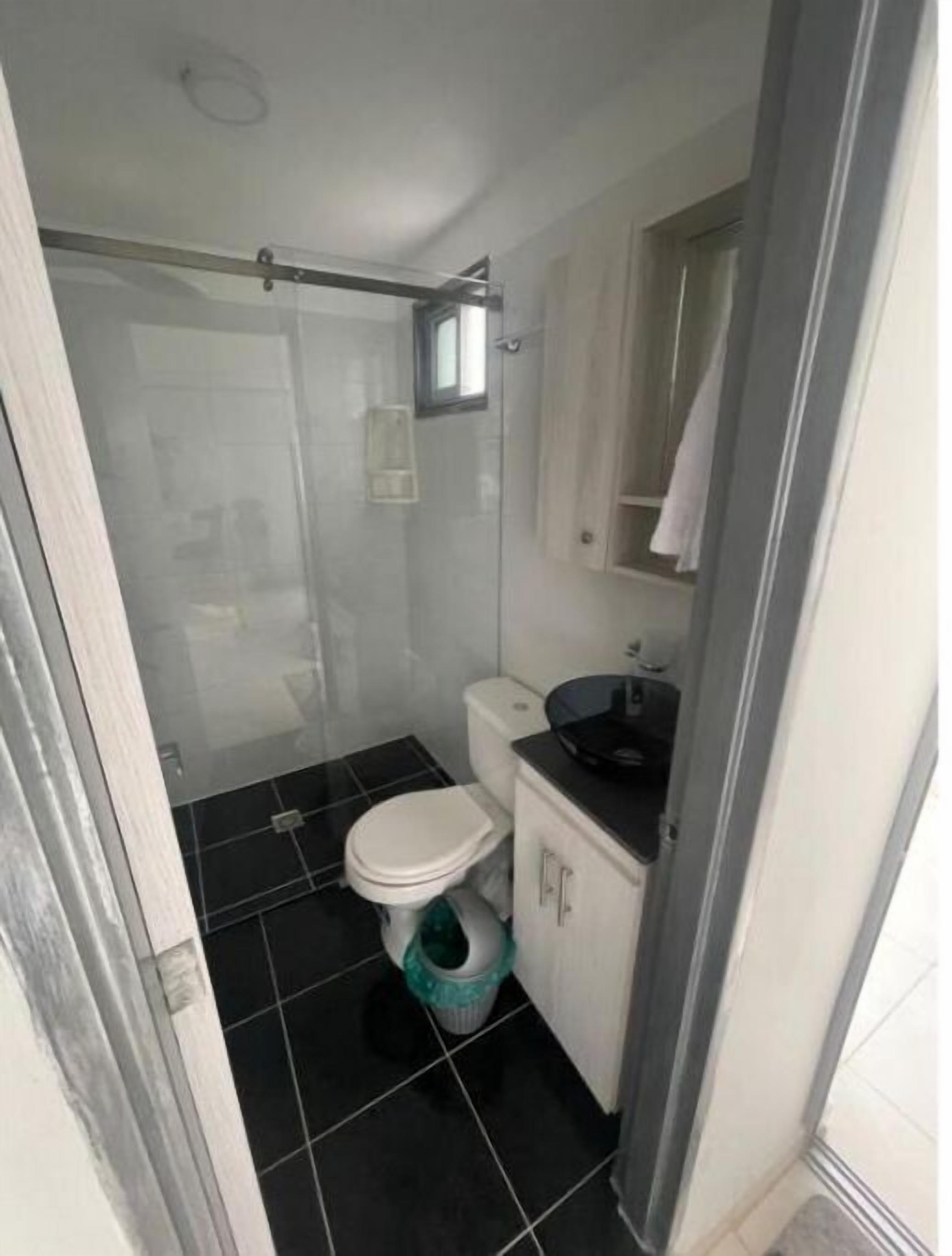 A compact bathroom with a toilet, sink, and shower area.