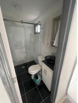 A compact bathroom with a toilet, sink, and shower area.