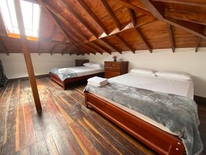 A bedroom with two wooden beds, a wooden dresser, and a sloped wooden ceiling.