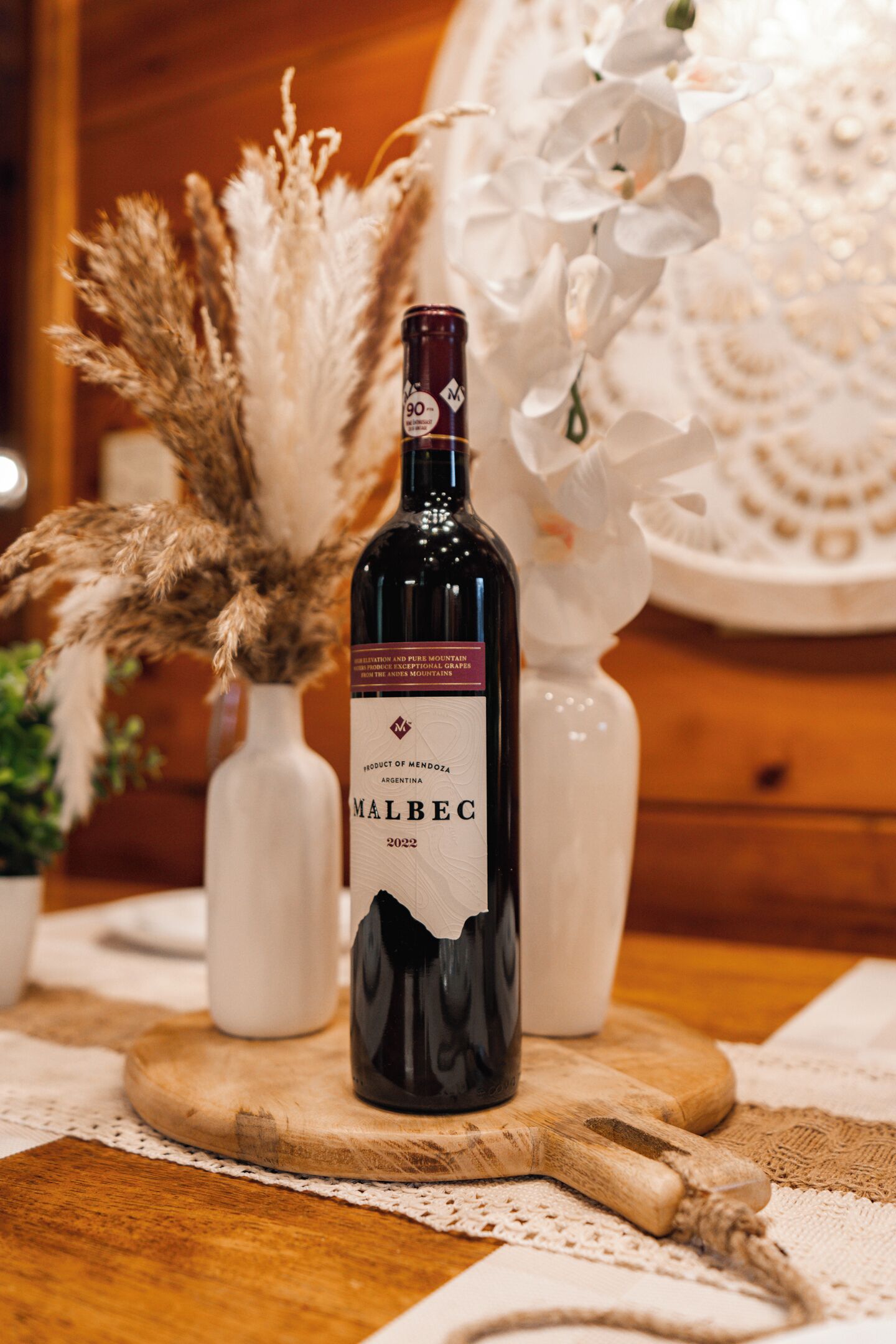 En flaska Malbec-vin på en träbricka, med en spetsduk under.
