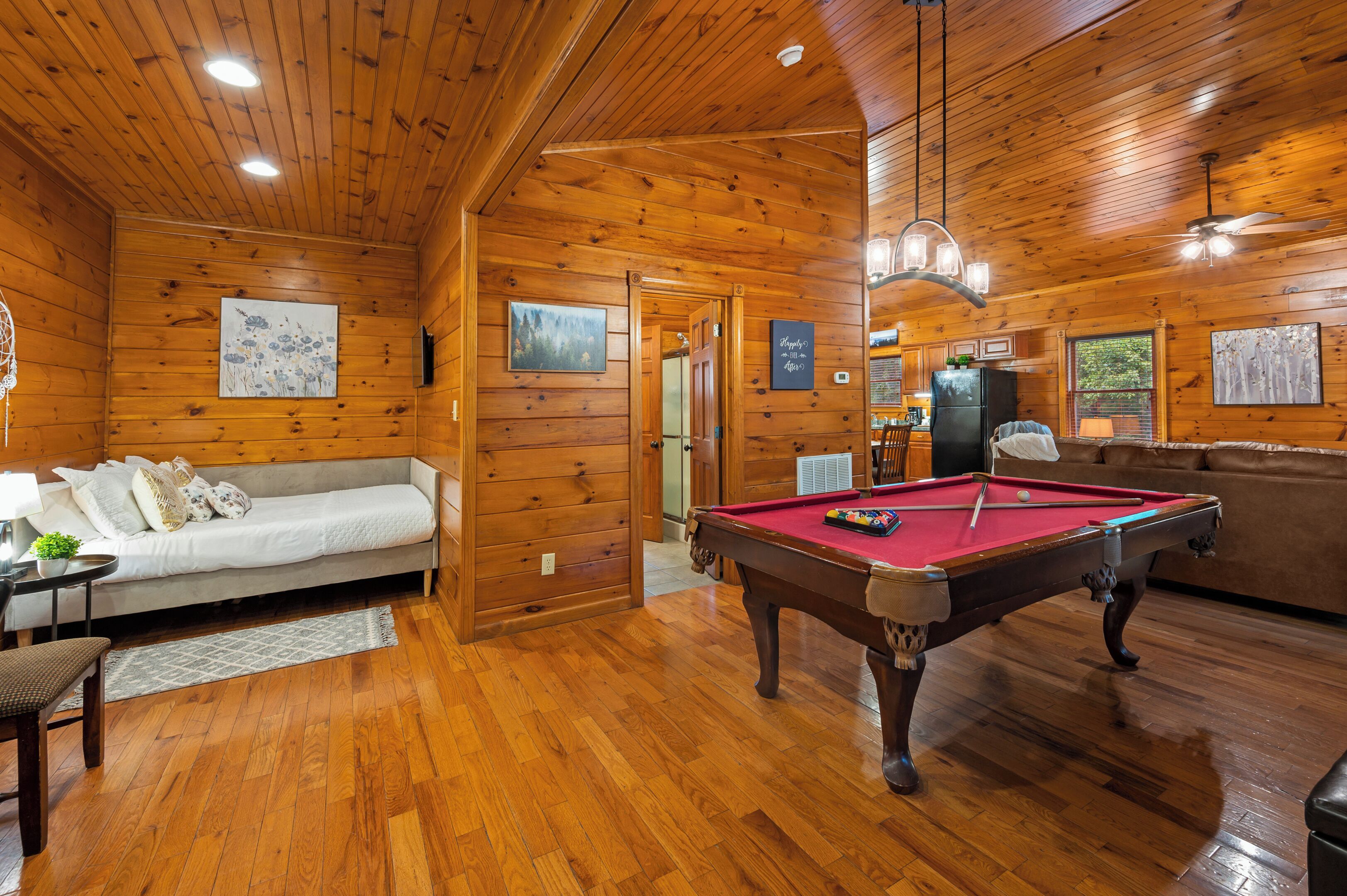 Interior de una cabaña de madera con mesa de billar, sofá y comedor.