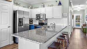 Una cocina moderna con armarios blancos, electrodomésticos de acero inoxidable y una encimera de granito.