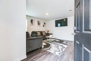 A modern living room with a grey sofa, a coffee table, and a patterned rug. - 3BR Moments from Goodfellow AFB! (San Angelo)