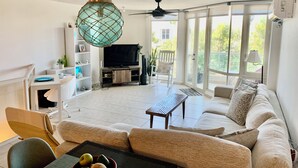 A spacious living room with a sofa, a coffee table, a TV, and a ceiling fan. - Paradise in Rio Grande, Puerto Rico Right Next door to Four Seasons (Río Grande)