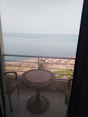 Enjoy a tranquil beach view from this balcony with a wicker table and chairs.