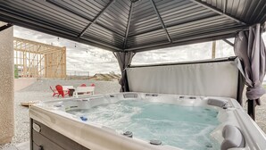 Een jacuzzi onder een overdekt gebied met uitzicht op een bouwplaats en rode stoelen op de achtergrond.