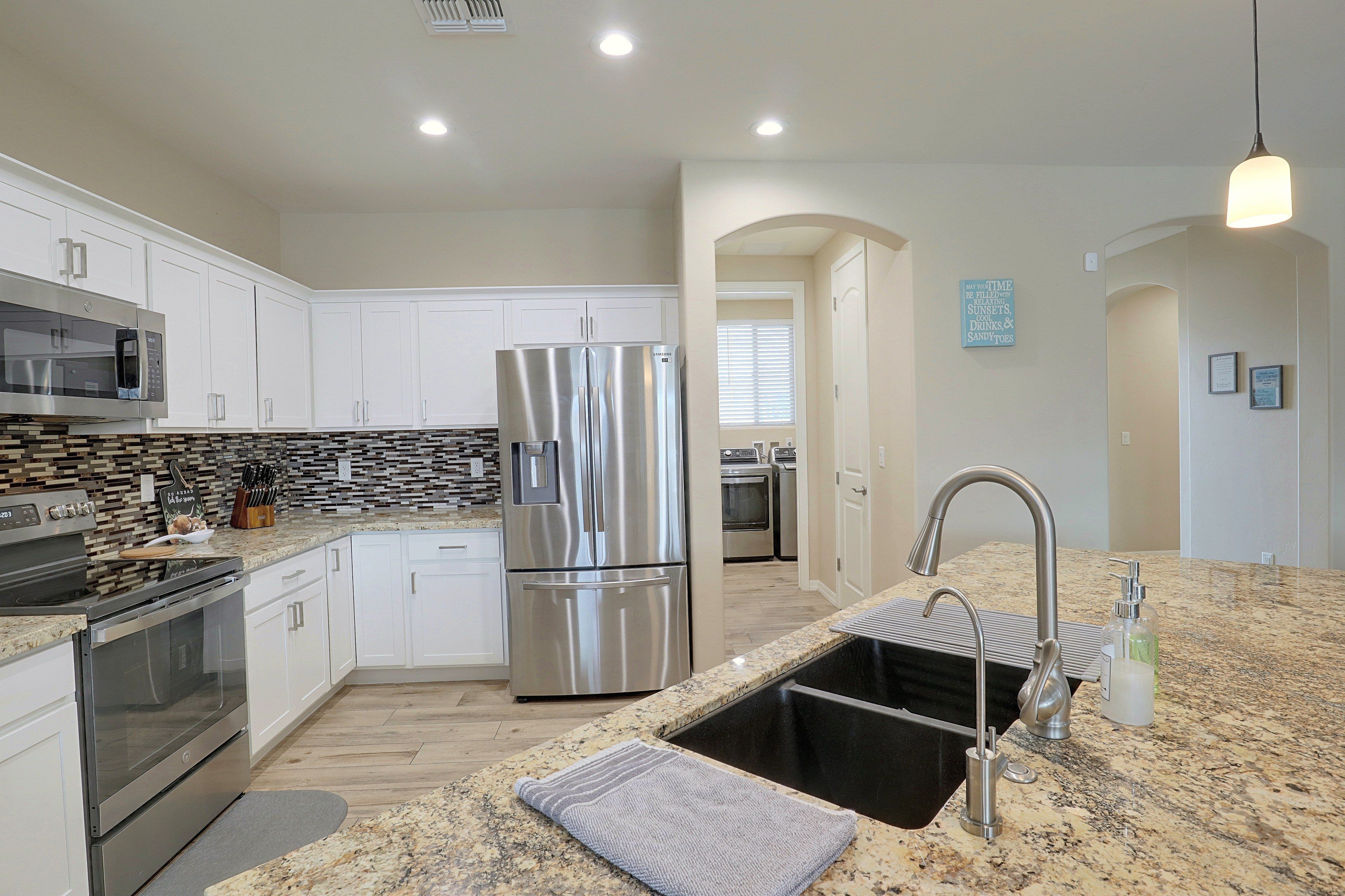 A modern kitchen with stainless steel appliances, a granite countertop, and a black sink.