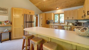 Eine geräumige Küche mit Holzausstattung, einem Edelstahlkühlschrank, einer großen Kücheninsel mit Hockern und modernen Geräten.