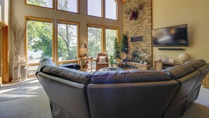 Ein geräumiges Wohnzimmer mit einer großen Ledersofa, einem Kamin und einem an der Wand befestigten Fernseher.