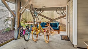 A covered porch with bicycles parked and a blue couch.