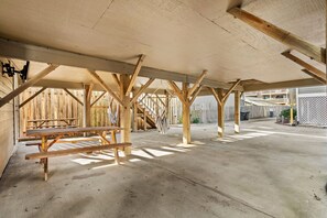 Un espace extérieur ouvert, mais abrité, doté d’un sol en béton et de poutres en bois soutenant un toit.