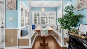 A beach-themed room with a wooden table, white walls, and a sign that reads "BEACH HOUSE".