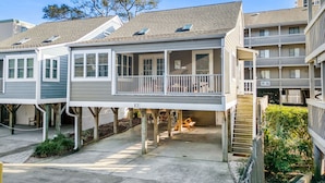 A multi-story residential building with a covered porch and a staircase leading to the upper levels.