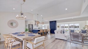 A spacious living area with a dining table, chairs, a sofa, and a view of the outside. - 530 Coastal Cabana – Waterfront Pool Home w/ Hot Tub, Dock, Golf Cart & Walk to Beach (Indian Rocks Beach)