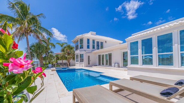 A modern two-story house with a swimming pool, outdoor seating, and palm trees. - 530 Coastal Cabana – Waterfront Pool Home w/ Hot Tub, Dock, Golf Cart & Walk to Beach (Indian Rocks Beach)