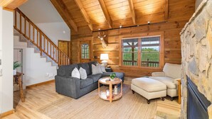 A log cabin interior with a staircase, a fireplace, a sofa, a coffee table, and a lamp. - Delightful Cabin near Blue Ridge Mountains (Blowing Rock)