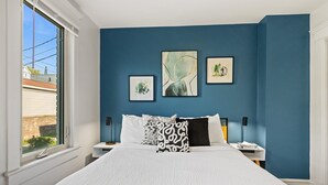 Un dormitorio con una cama grande, dos mesitas de noche y tres cuadros enmarcados en la pared.