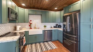 A kitchen with teal cabinets, stainless steel appliances, and a wooden ceiling. - Cozy Cabin in the Pines with Views! (Prescott)