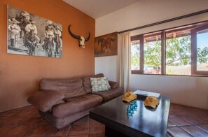 A room with a brown leather sofa, a coffee table with a skull and a hat, and a painting of cowboys on horseback.