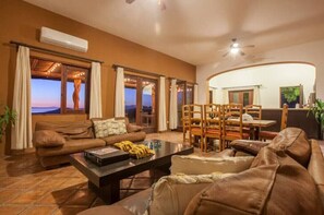Relax in this inviting space with a curved wall, leather sofa, and large windows offering a view of the outdoors.